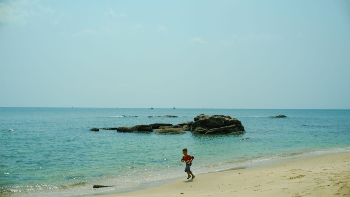 bambino gioca sulla spiaggia tropicale
