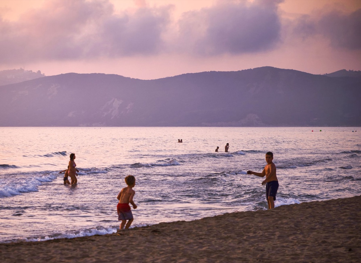 Children playing on a beach with a snorkeling gear nearby and a nearby boat with snorkeling equipment