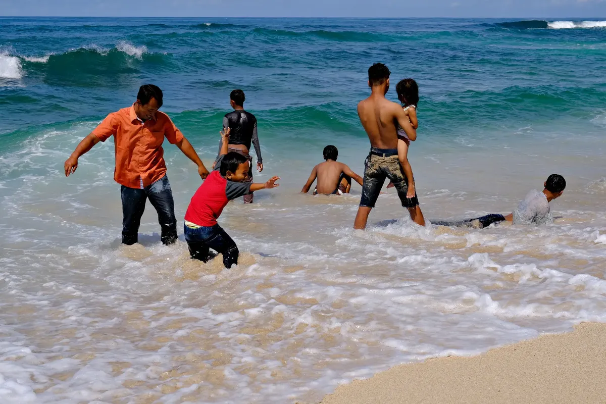家族が晴れた日の浜で海の波に遊び、元気な夏の瞬間を楽しむ。