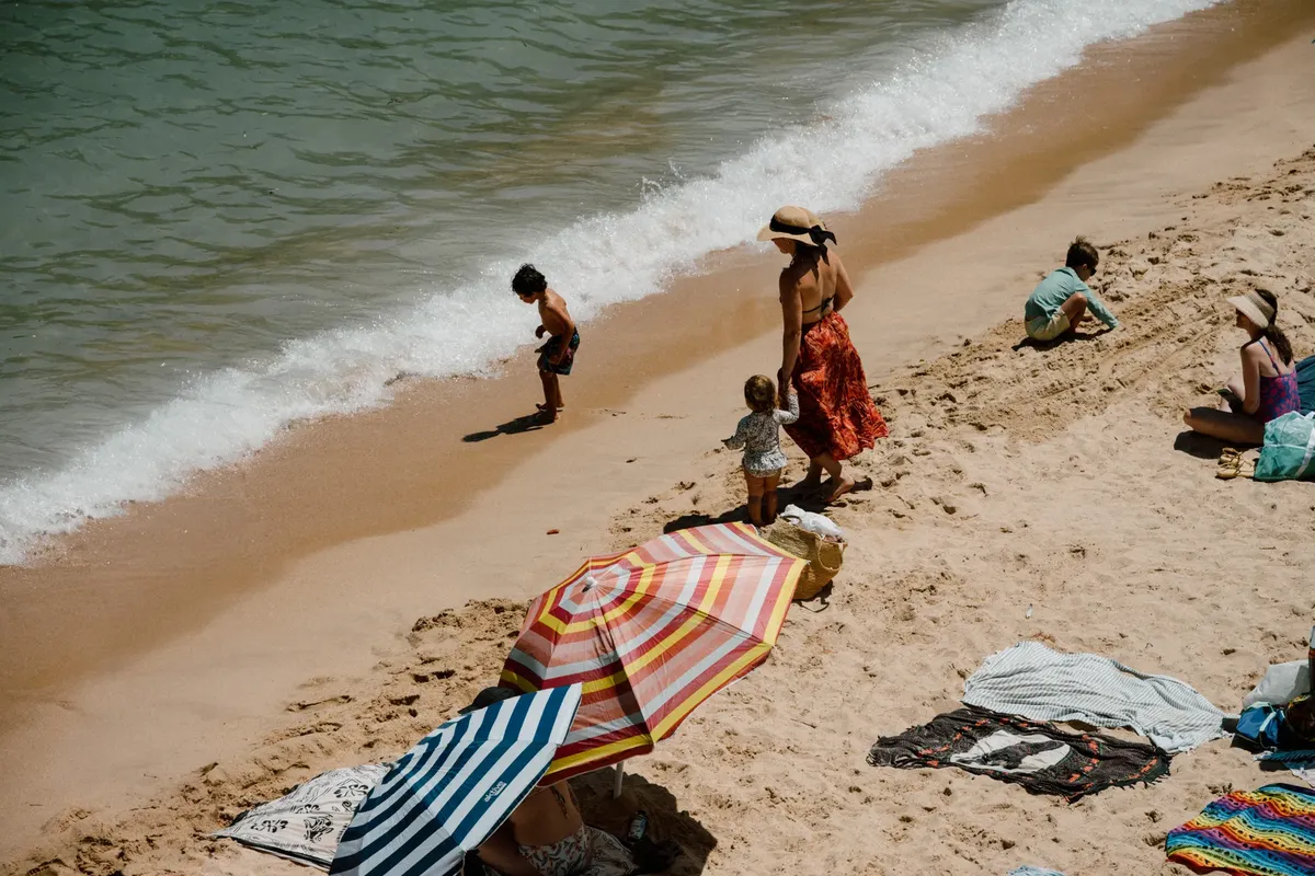 Children and adults relax and play on a sandy beach in Barcelona, Spain.